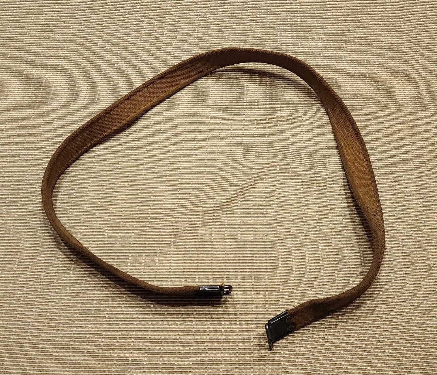 Full length view of 1942 Enfield khaki web sling with blackened brass hooks at each end