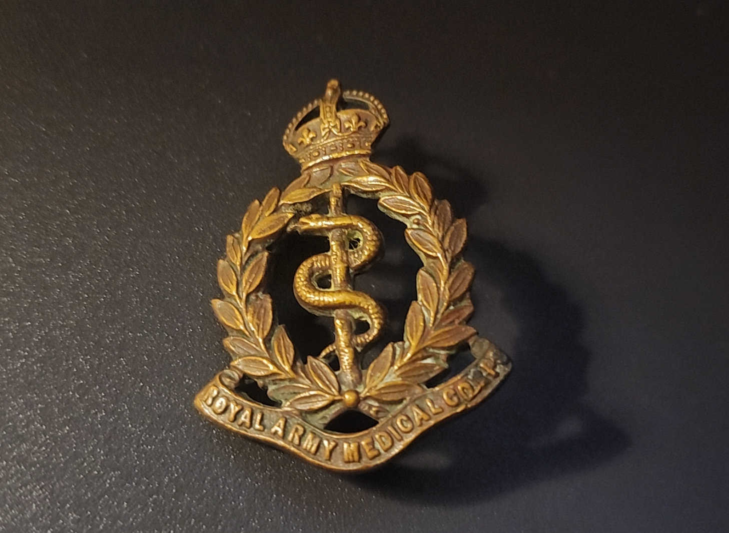 Obverse of RAMC cap badge showing Rod of Asclepius, laurel wreath and King&rsquo;s Crown