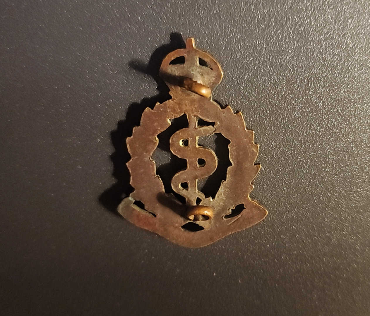 Reverse of RAMC cap badge with attachment fittings