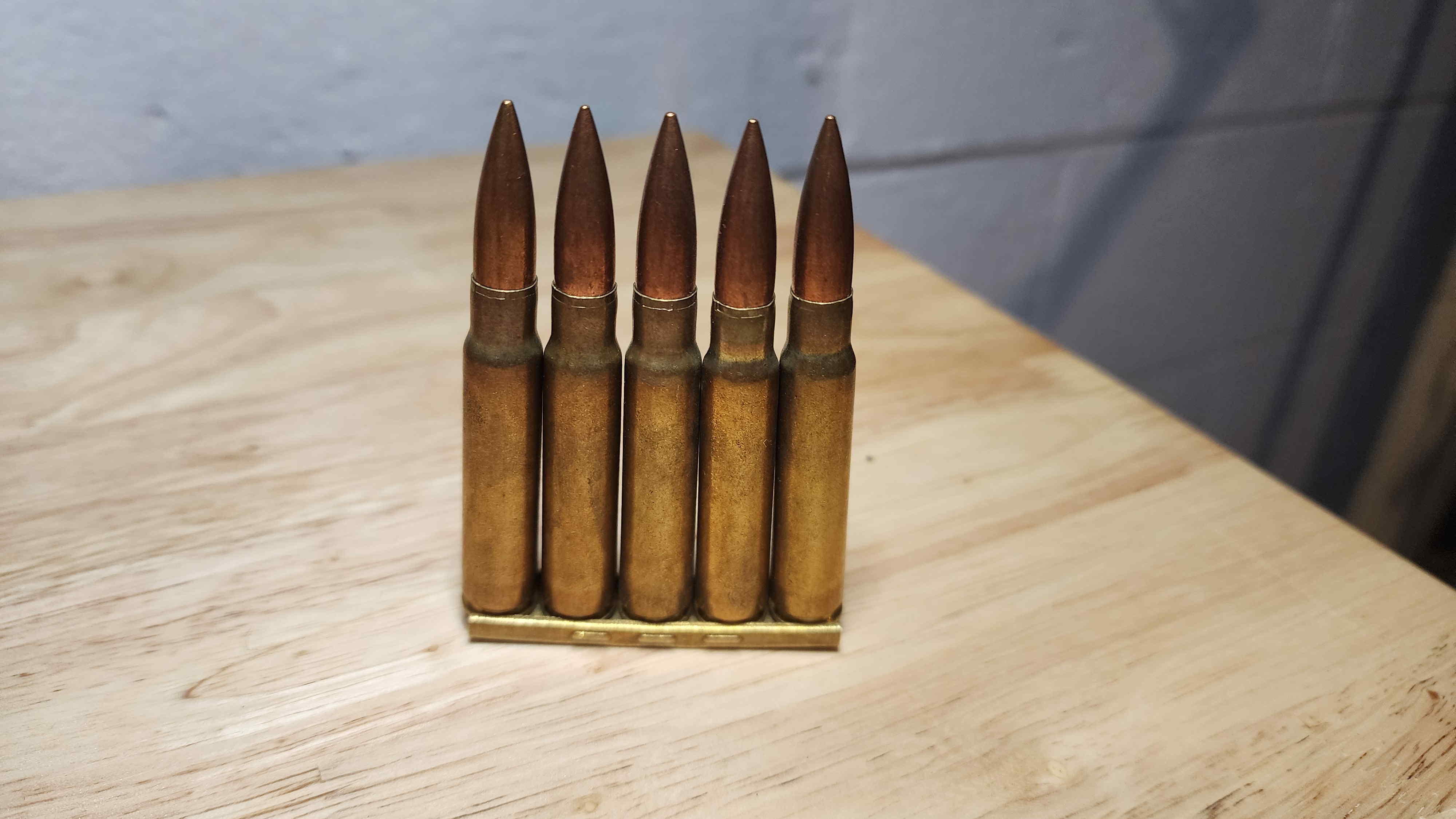 Five 1951 Czechoslovak 7.92×57mm Mauser cartridges arranged in a clip for display