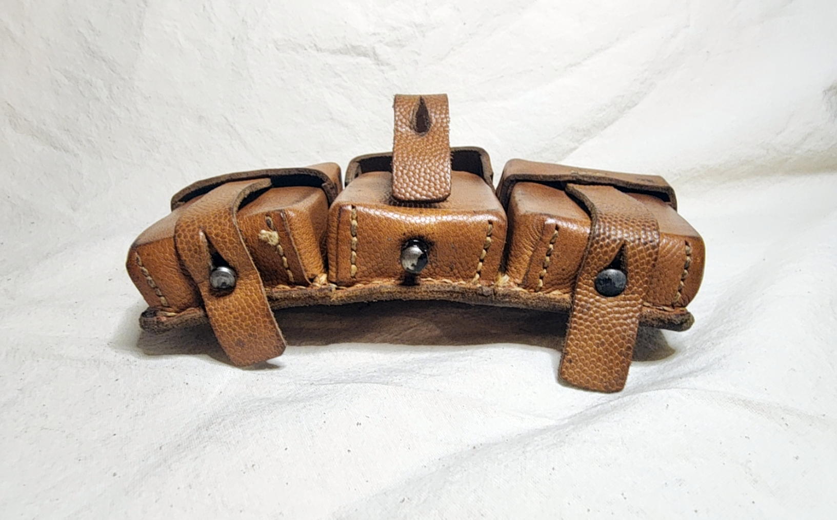 Underside of Kar98k ammunition pouch showing three metal fastening studs and raised center closure strap