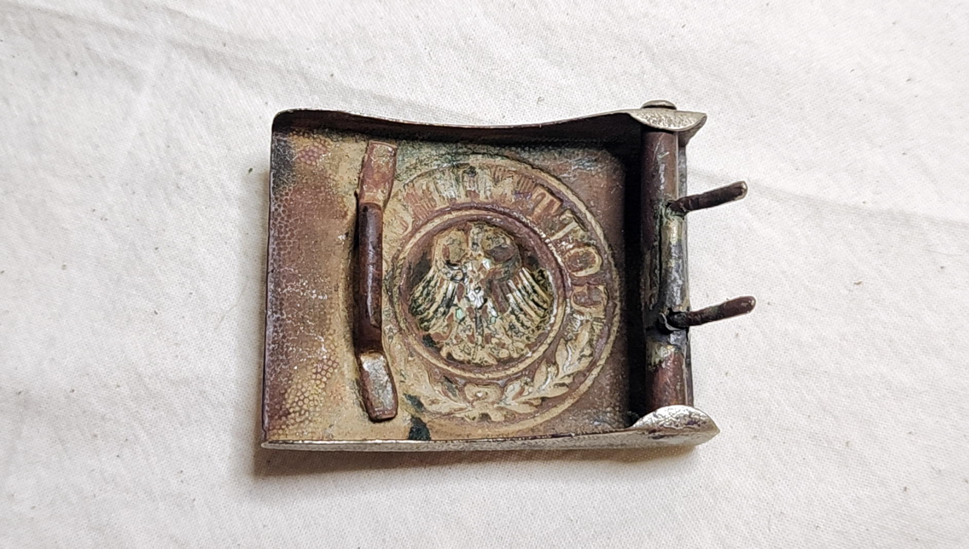 Reverse of the Reichswehr buckle with recessed stamped design, two catch attachments, and roller with two adjustment prongs