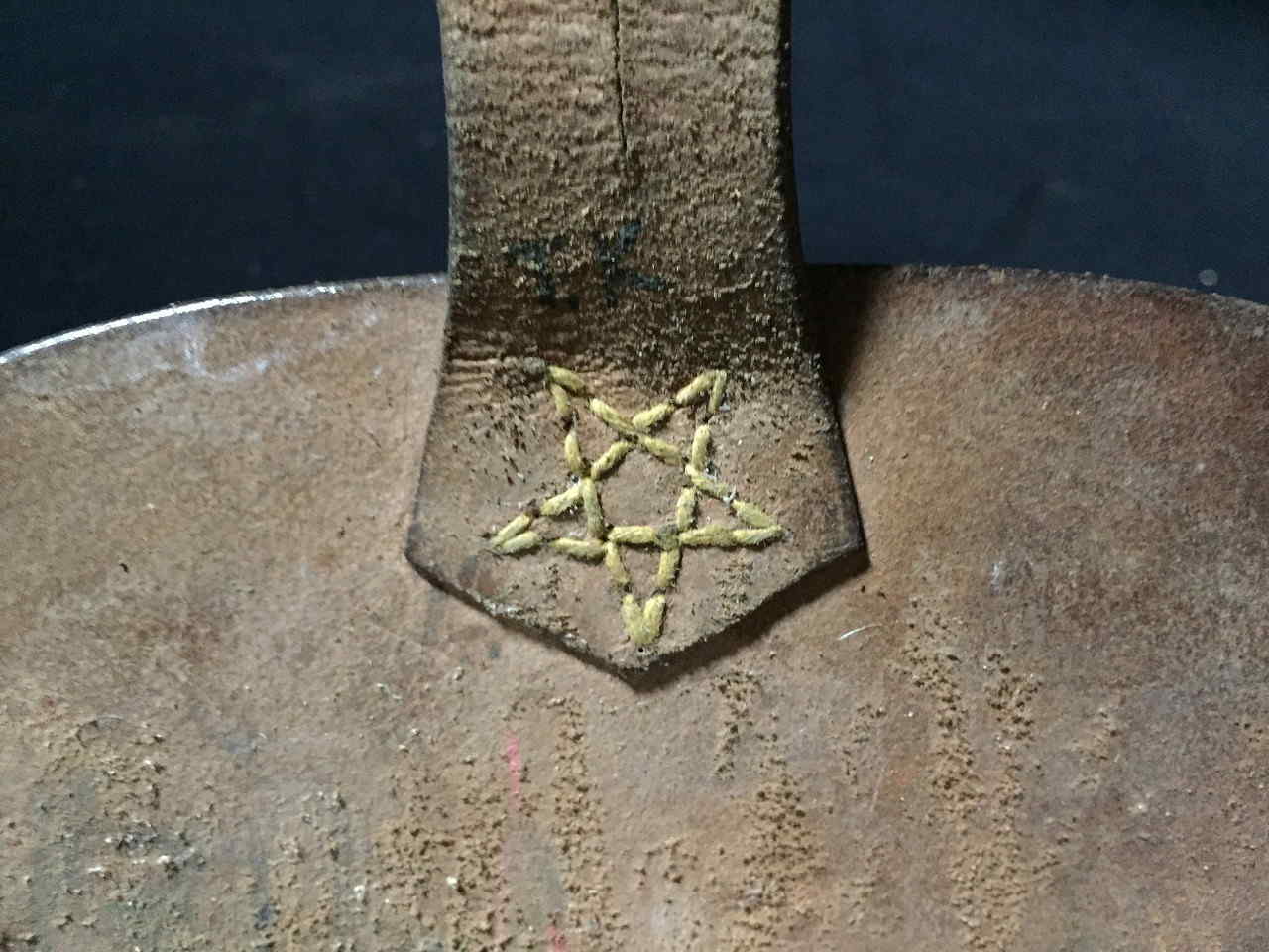 Close view of leather closure tab with stitched star and hand-applied TK marking