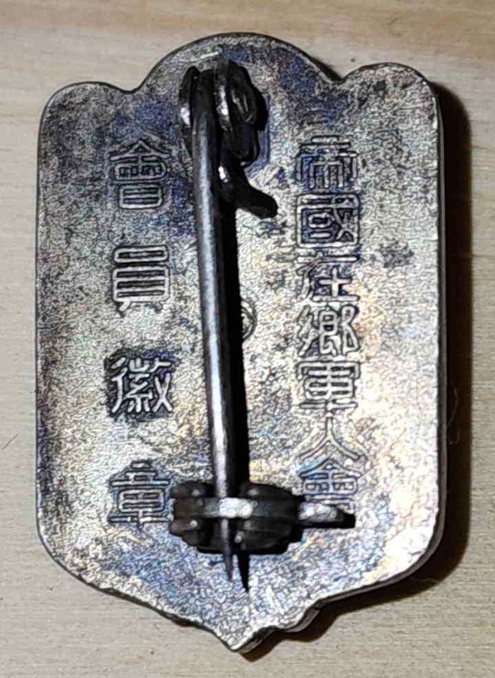 Reverse of Imperial Japanese Military Reservist Association badge showing vertical inscription and pinback
