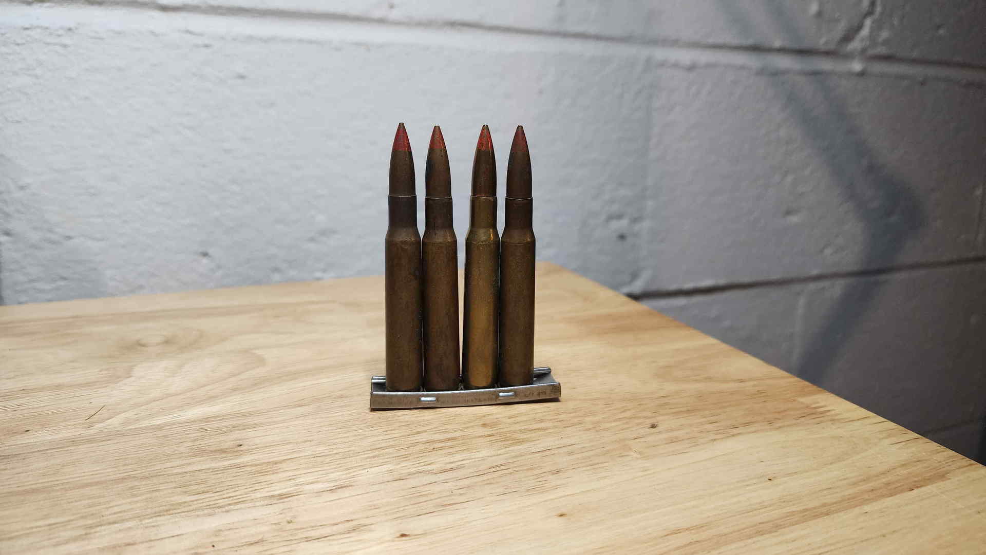 Three red-tip DM 42 tracer cartridges and one plain-tip DM 42 ball cartridge arranged in an M1 Garand en bloc clip
