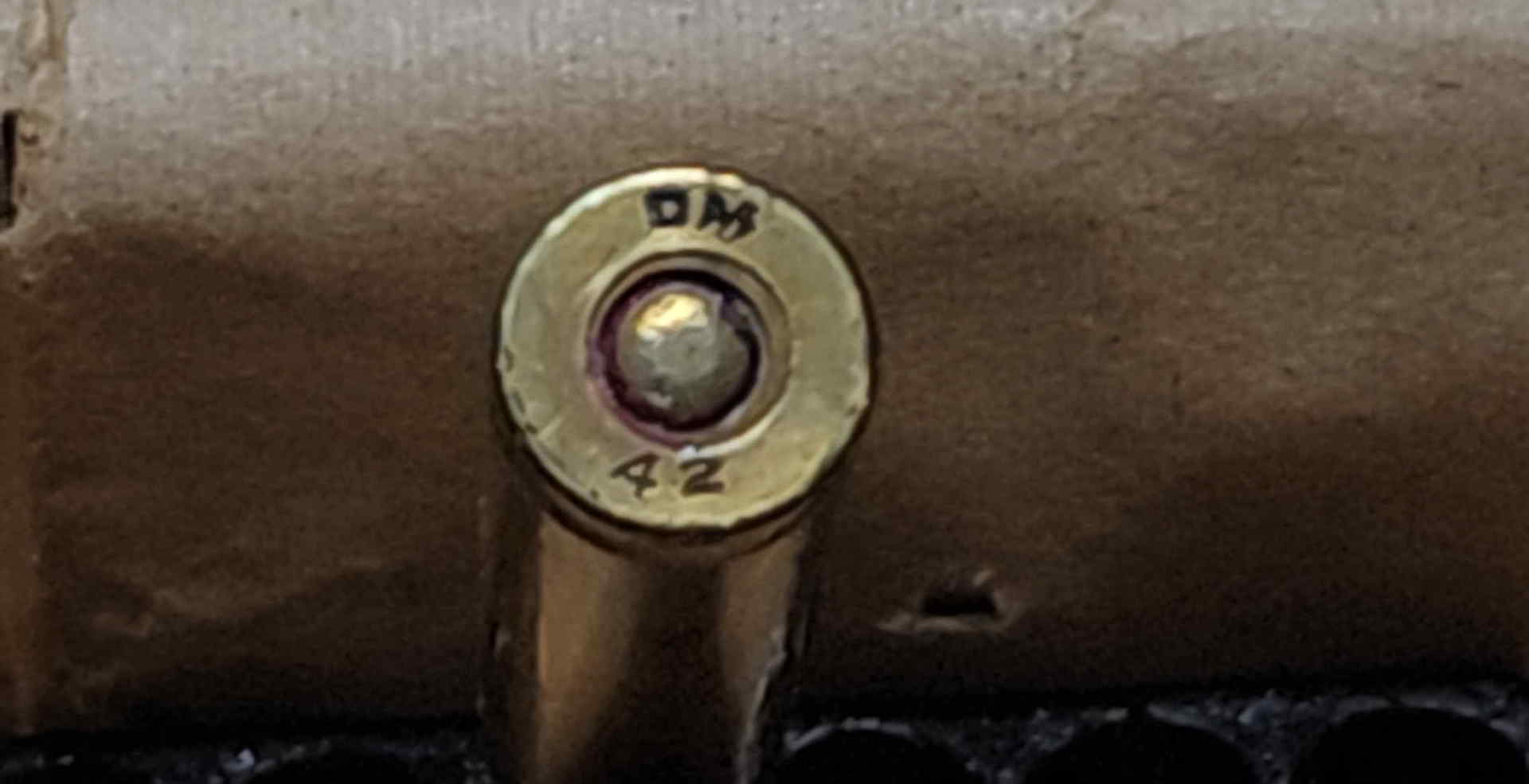 Close-up of a DM 42 headstamp with tightly spaced plant initials