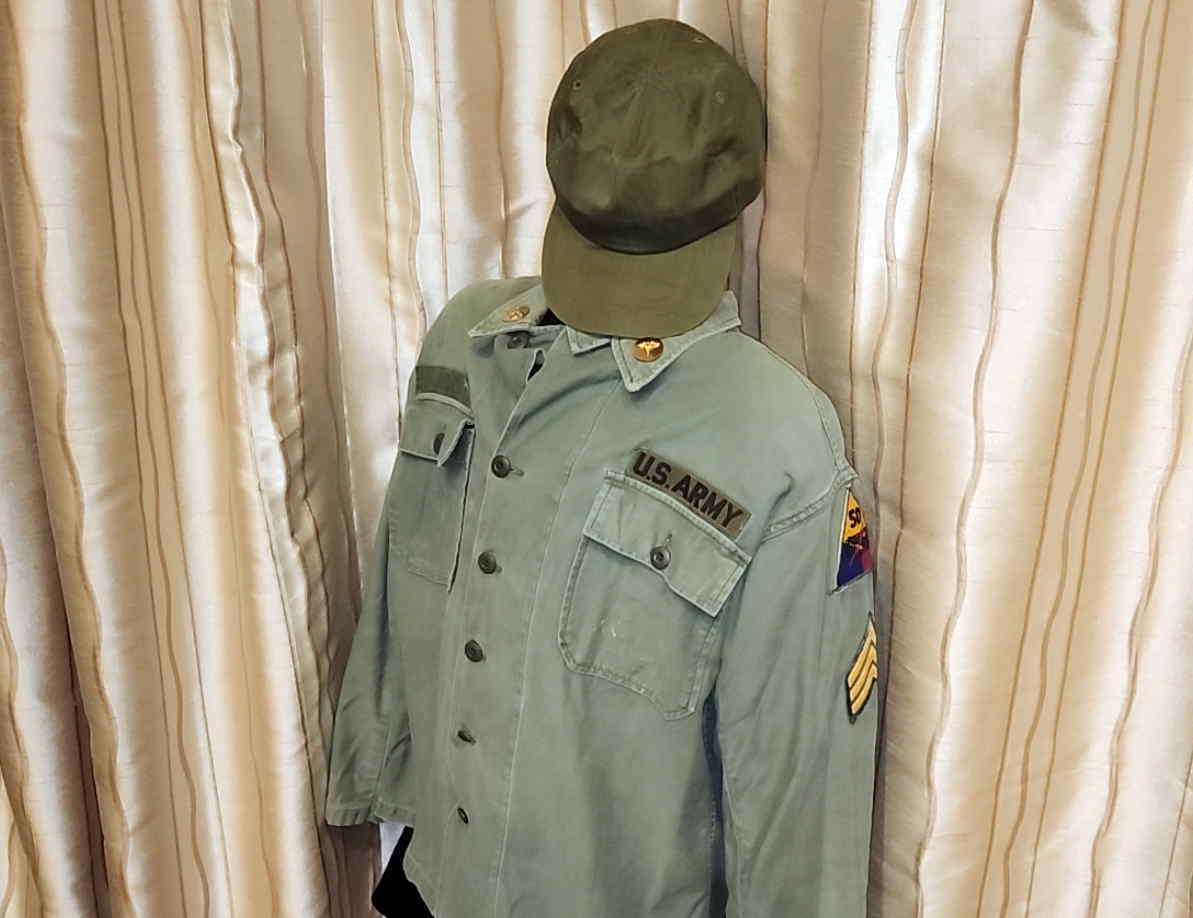 Preserved OG-107 utility shirt with division patch, Sergeant chevrons, U.S. Army tape, and utility cap